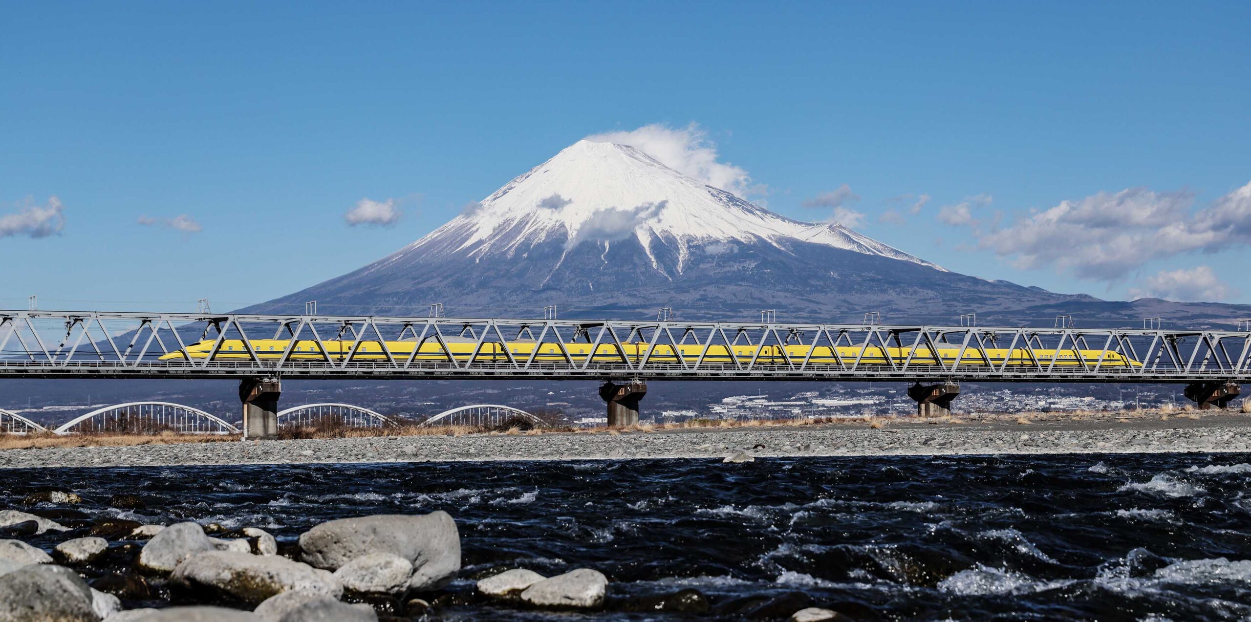 富士山を背景に、富士川を渡る点検車両「ドクターイエロー」の「T4編成」=2025年1月28日午後0時41分、静岡県富士市